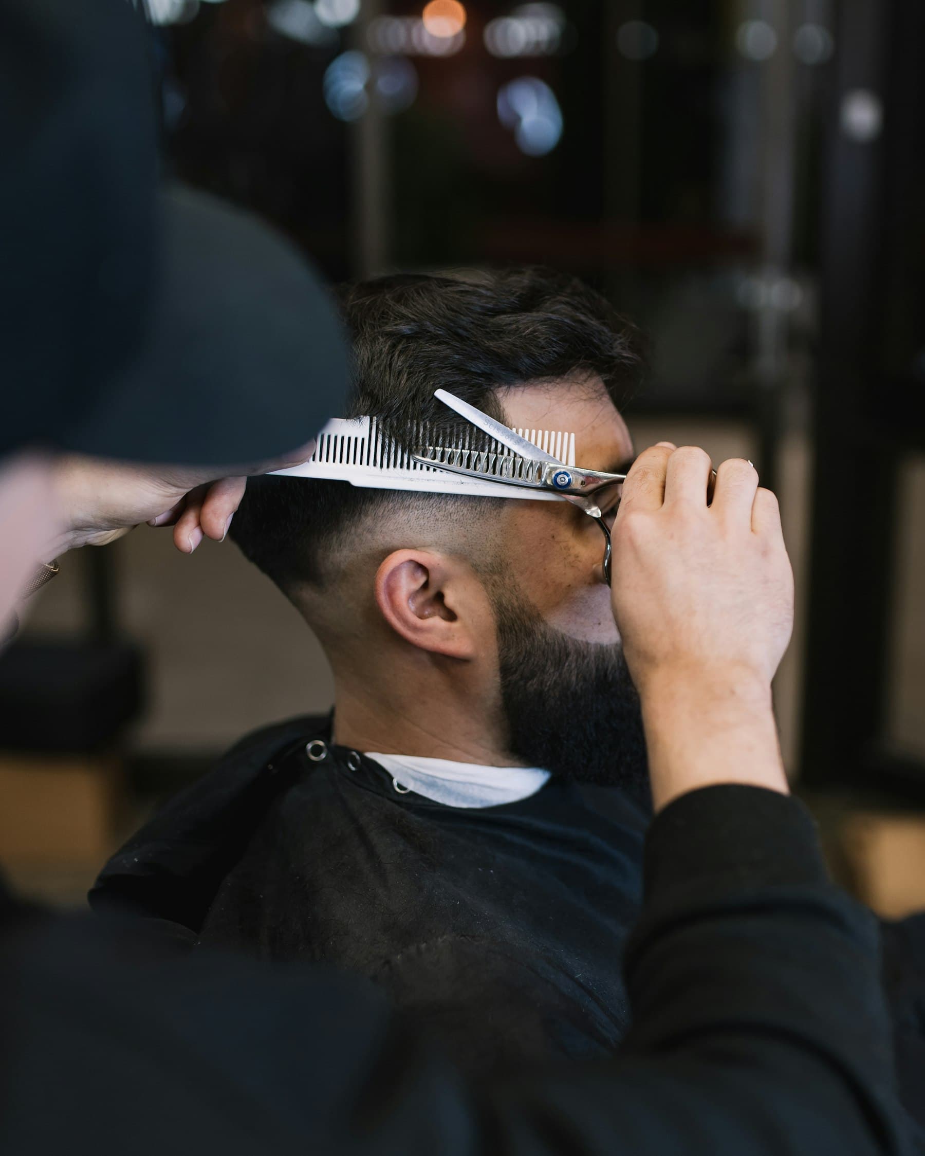 Barbero peinando y cortando con tijera sobre peine